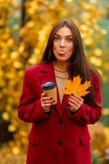 Portrait of a young woman with leaves in an autumn park. A stylish girl in a burgundy jacket strolls outdoors. Autumn fashion.