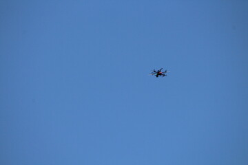 Drone flying on isolated blue sky. Drone frozen in flight on a blue sky background