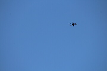 Drone flying on isolated blue sky. Drone frozen in flight on a blue sky background