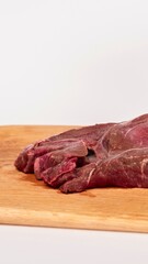 Thinly sliced raw beef steak on a wooden cutting board