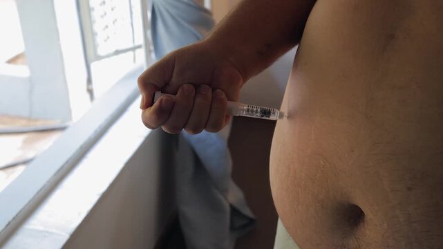 Man injects subcutaneous medication into belly with injection pen