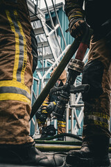 Firefighters handling hose at training tower during firefighting drill