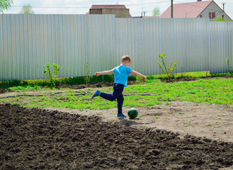 A boy plays football in the garden of a house
