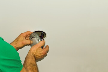 Close-up of a man repairing an electric ceiling light