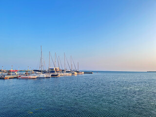 Sailboats docked at the marina under a clear blue sky at sunset