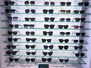 Sunglasses displayed on glass shelves in a retail store showcase a variety of stylish frames and lenses, creating a fashionable and modern display.