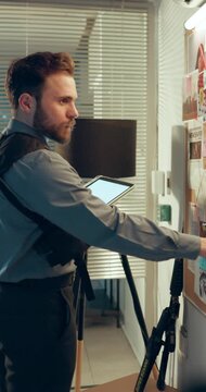 Investigation, night or man in office with tablet, cross reference or information on evidence board. Mind map, tech or detective at police station with pointing, crime or clue analysis on late shift.