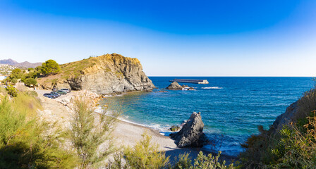 Rocky cove at Playa de la Gola in Llançà, Costa Brava, with turquoise sea, cliffs, sparse vegetation and a calm, sunny coastal atmosphere.