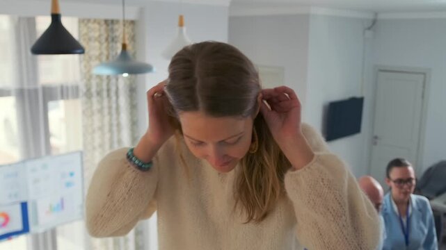 A young woman climbs up with the support of colleagues and prepares to fall into their hands during a trust-building exercise in a modern office. Teamwork, confidence, and cooperation concept.