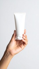 Hand holds a white, clean tube against a plain background