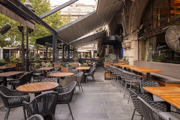 Modern open-air café with wooden furniture and fabric awnings