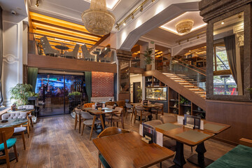 Stylish double-level restaurant featuring wooden décor, chandeliers, and warm ambient lighting