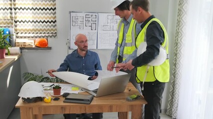 white architect reviews construction plans with crew in highvisibility vests, foreman points to foundation drawing, safety helmet and tape measure on table, site briefing focused on compliance