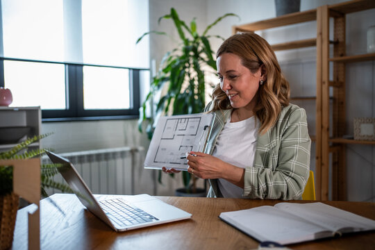 Woman architect showing blueprint during video call remote work