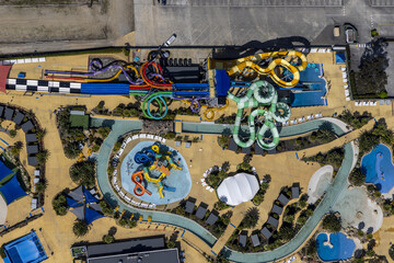 Aerial view of vibrant water slides twisting and turning against the tan landscape of the Gumbuya World theme park, Tynong North, Victoria, Australia.