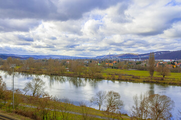 Calm river flowing through a scenic valley surrounded by mountains under a cloudy sky in late autumn