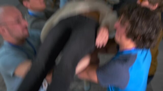 Female participant gently falls backward with eyes closed, fully supported by her colleagues. Powerful symbol of trust, safety, group cohesion in the workplace. Team takes part in trust fall exercise