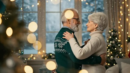 Happy senior couple dancing by a Christmas tree, enjoying a romantic moment while snow falls outside during the festive holiday season - Powered by Adobe