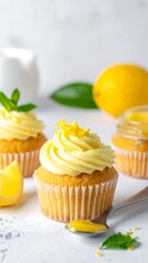 Lemon cupcakes on white, with a lemon and mint leaves nearby