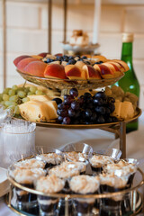 Elegant Dessert Spread Featuring Fresh Fruit, Mini Cheesecakes, and Wine on a Tiered Stand, Golden Accents, and Light Textures