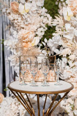 Elegant Wedding Champagne Toast Setup with White Floral Wall, Gold Table, and Crystal Flutes Luxury Celebration Decor.
