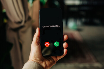 Hand holding phone displaying unknown call scam alert