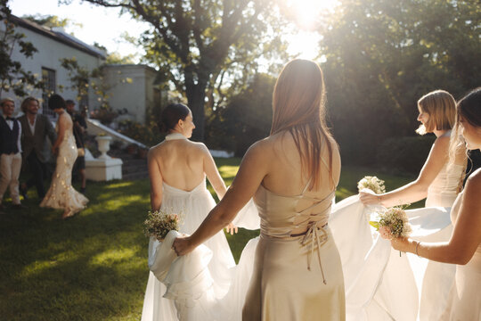 Bride walking with bridesmaids during a sunny outdoor wedding ceremony