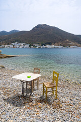 Table with chairs on the beach in Xilokeratidi, facing the Katapola harbor. Amorgos, Cyclades, Greece