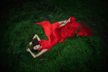 woman dressed in a flowing red gown reclines on soft green moss in a dimly lit forest. scene evokes a magical, serene atmosphere as evening approaches