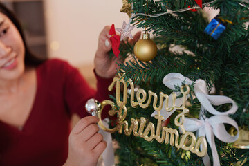 SSTK Christmas: Woman decorating tree with 'Merry Christmas' sign and ornaments