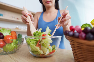 Food Wellness: Woman mixing fresh salad with wooden utensils