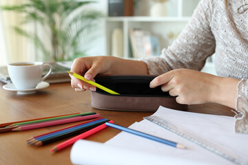 Woman hand putting pencil on case on a table
