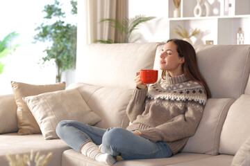 Woman relaxing in winter at home smelling coffee