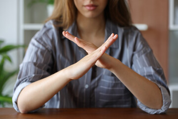 Woman hands gesturing x or stop on a table