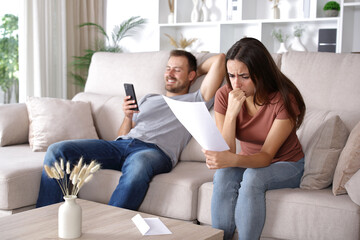 Worried woman reading letter and happy husband ignoring her