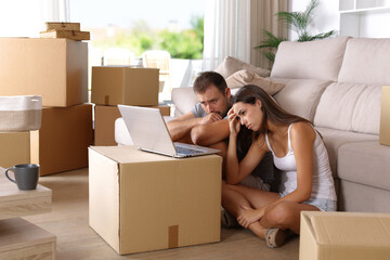 Sad couple moving home checking bad news on laptop
