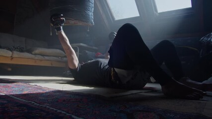Man training with boxing gloves in a quiet attic early in the morning