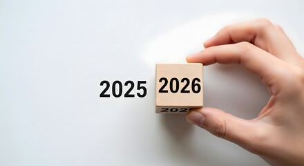 A person's hand flipping a wooden block to change the year from 2025 to 2026, symbolizing new beginnings and future planning