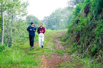 Obraz premium Happy Two Young Asian Males Enjoying Jogging At Lush Forest Trail