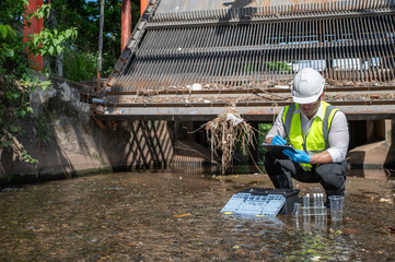 Environmental engineer collect water samples from drainage canals around the city and quality test