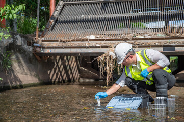 Environmental engineer collect water samples from drainage canals around the city and quality test