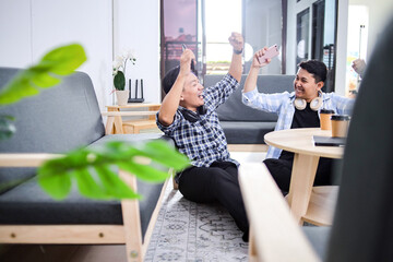 Happy Friends Celebrating Victory With Smartphone During Break Time At Office