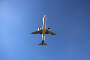 white silver Commercial jet plane landing passenger international modern airplane isolated on blue sky background. Bottom view