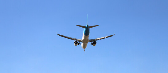 white silver Commercial jet plane landing passenger international modern airplane isolated on blue sky background. Bottom view