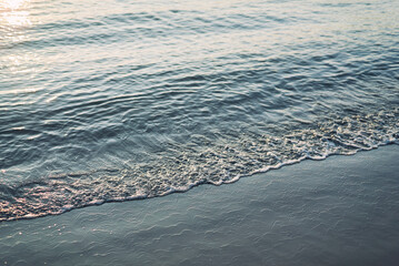 Gentle Ocean Waves on Sandy Seashore at Sunset
