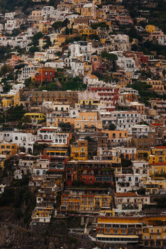 Aerial view of sun-drenched houses cascade down the hillside, creating a vibrant tapestry of colors against the deep green foliage, Positano, Campania, Italy.