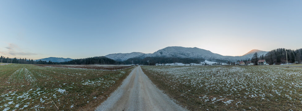 panoramica su un vasto ambiente naturale parzialmente innevato, tra l'alta pianura e la montagna, in Slovenia, nel tardo pomeriggio, in inverno