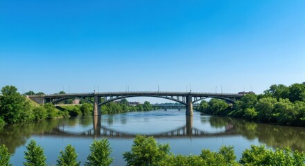 Stone bridge spans a calm river under a bright blue sky, surrounded by lush green trees