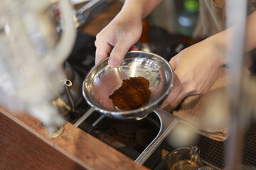 Close up of focused barista hand preparing fresh ground coffee in steel bowl. careful morning routine for making perfect aromatic beverage in cafe
