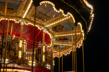Close-up view of a beautifully decorated vintage carousel glowing with warm lights at night in Gdańsk, Poland